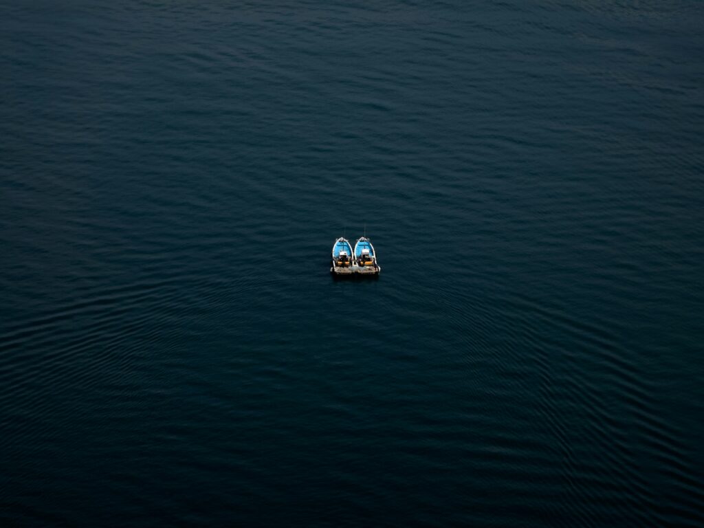 two small boats out at sea side by side