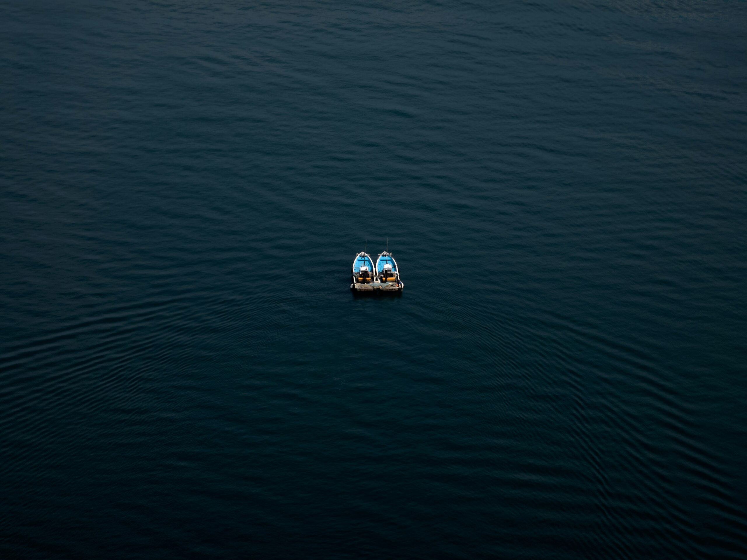two small boats out at sea side by side